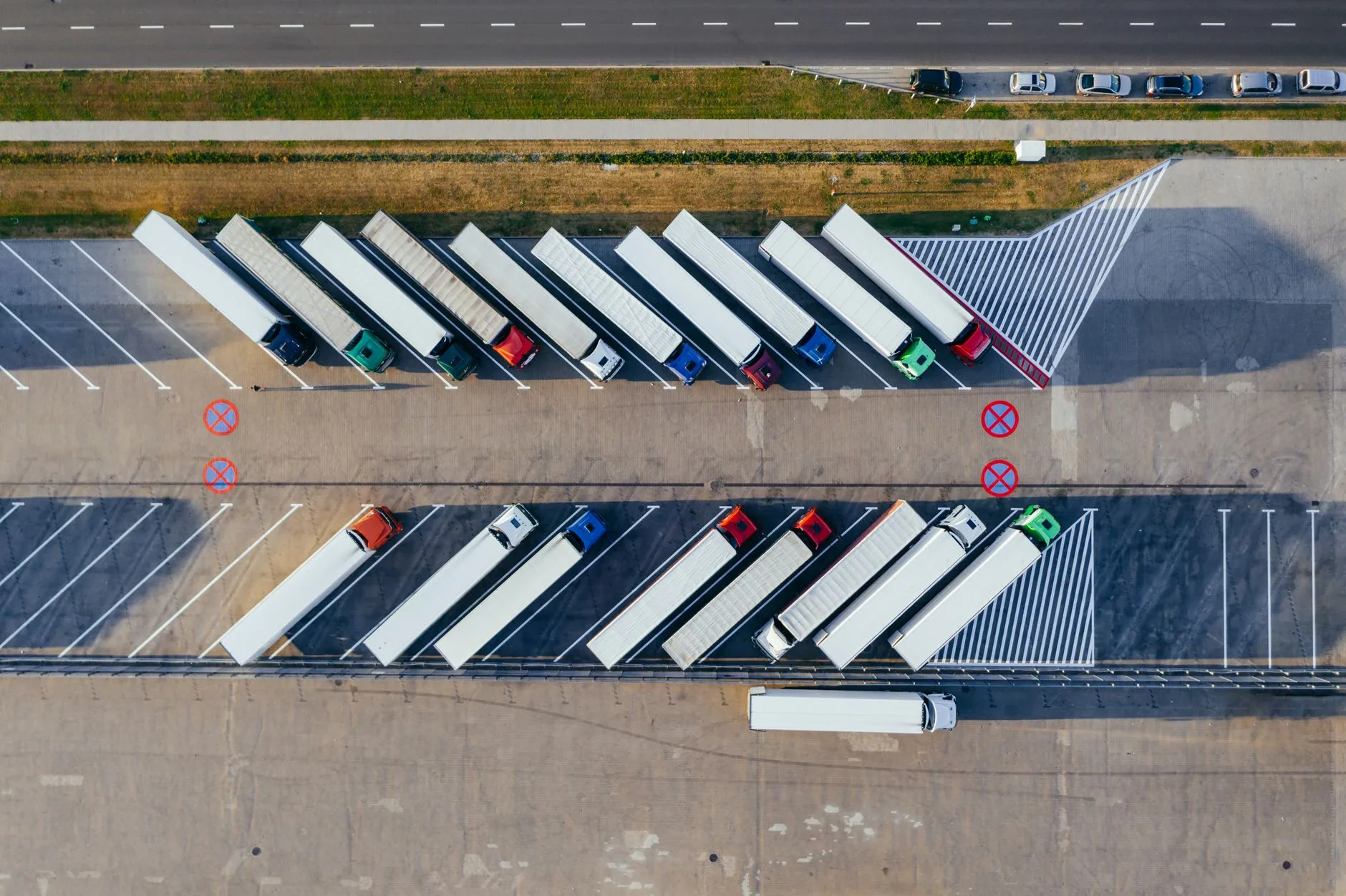 Vista aérea de tractocamiones con caja seca estacionados en fila en un patio de maniobras